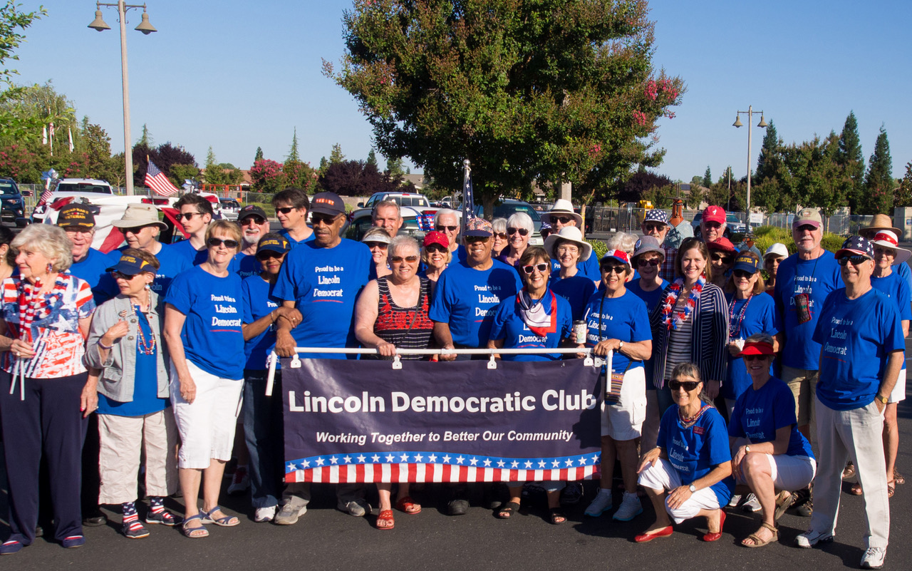 A group of people standing in front of a lincoln democratic club banner.